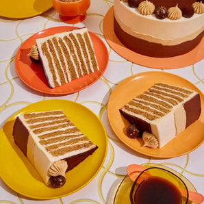 Tiramisu Cake slices on colorful plates with cream layers and gold-flecked truffle decorations by Crumbs & Doilies